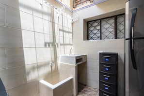 A bathroom with a shower, a sink, and a storage unit with numbered compartments. - Double/Triple Suite 18-103 (Bogotá)