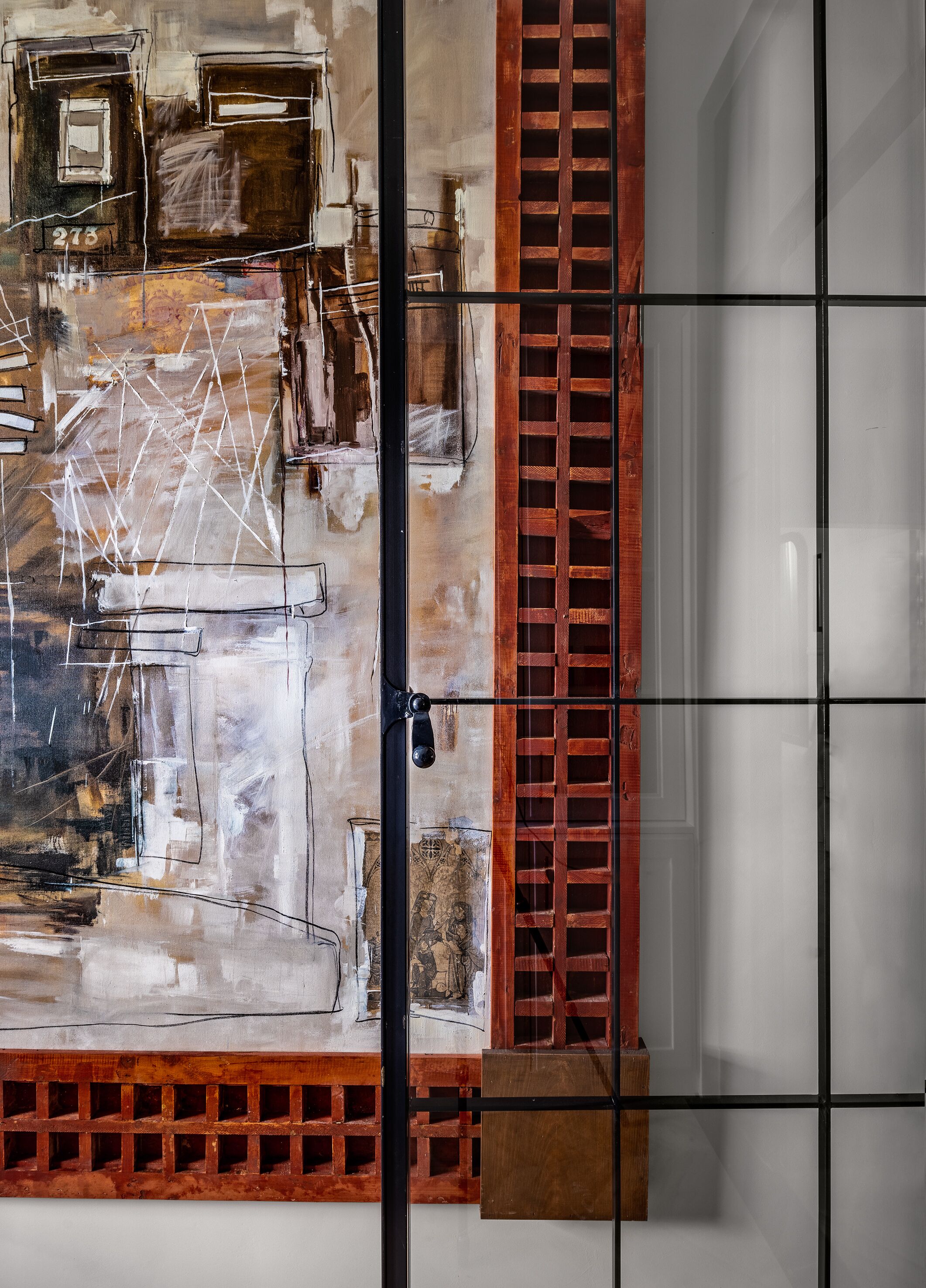 A room with a large abstract painting, a wooden lattice partition, and a door with a handle.
