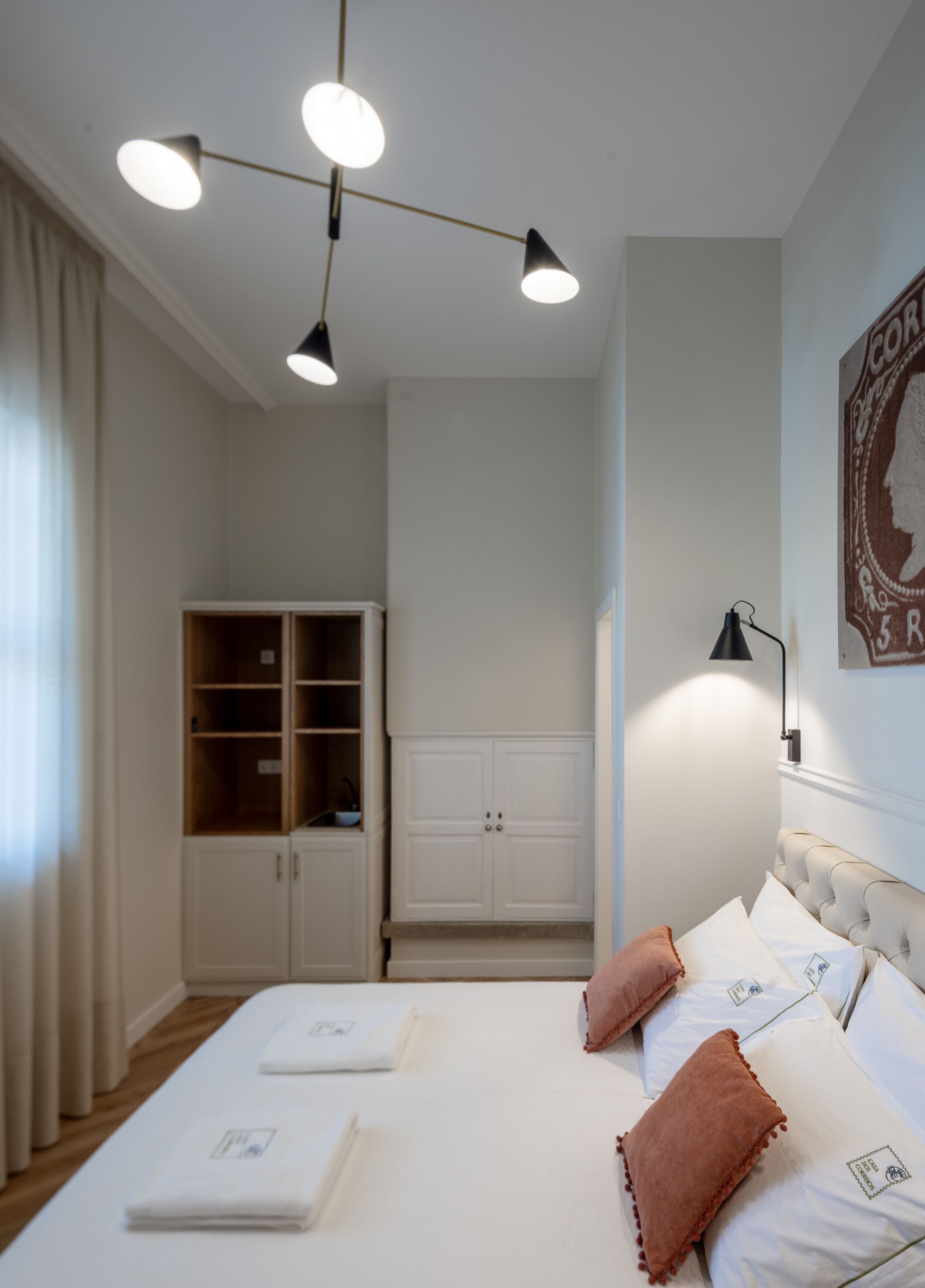 Une chambre à coucher moderne, avec un lit, des lampes de chevet, une armoire et un tableau accroché au mur.