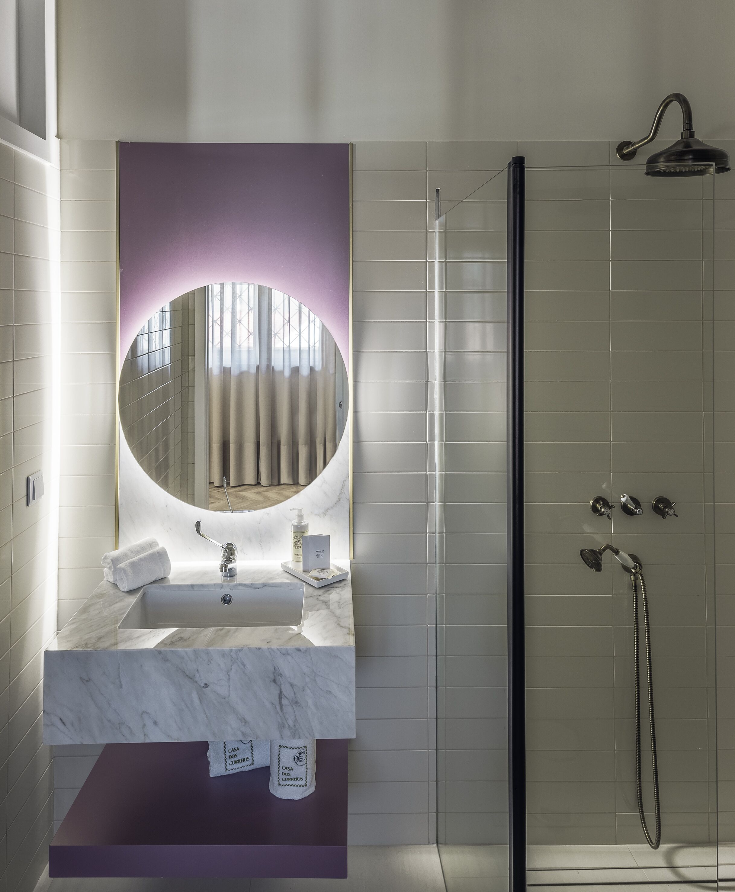 Un baño moderno con un lavabo de mármol, un espejo grande y una ducha con mampara de vidrio.