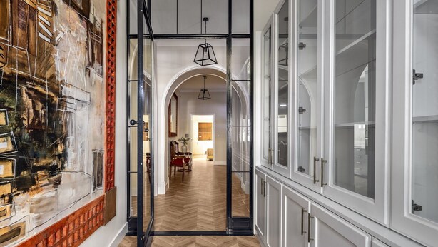 A hallway with a herringbone floor, a large painting on the left, and a glass-fronted cabinet on the right. - Casa dos Correios (Vila Real)