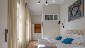 A bedroom with a bed, curtains, a wall-mounted light, a window, and a wall decoration. - Casa dos Correios (Vila Real)