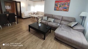 A living room with a sofa, coffee table, and a painting on the wall. - SAONA VILLAS (VN CUAD): villa for 8 people, private pool, wifi (Tres Calas)