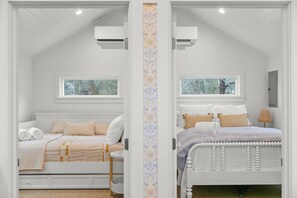 A bedroom with two beds, a window, and a door.