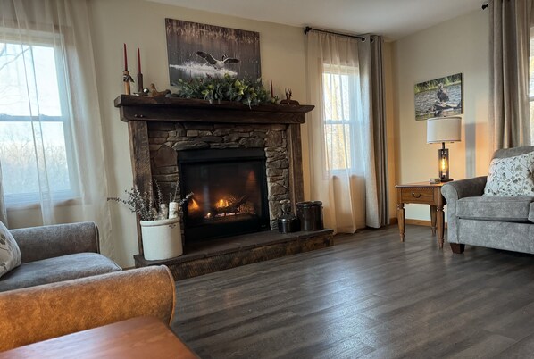 A cozy living room with a stone fireplace, a sofa, and a lamp.