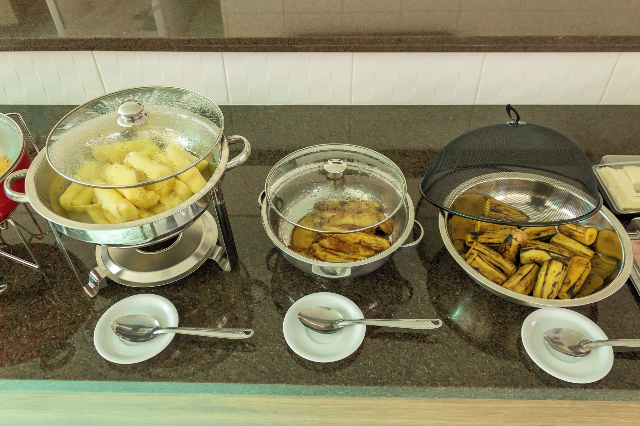 Een buffet met diverse gerechten, waaronder aardappelen, kip en bananen.