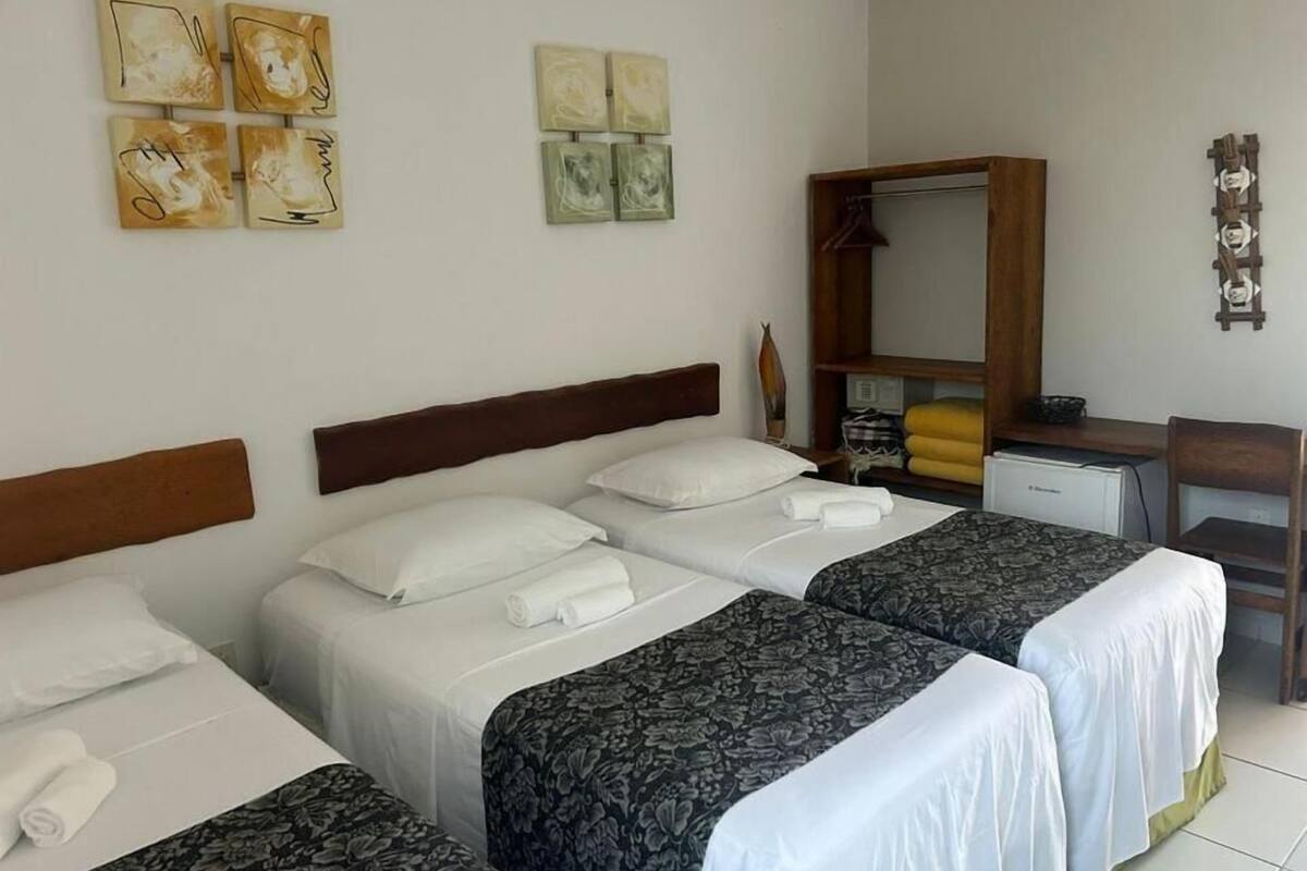 A hotel room with two beds, a desk, and a wardrobe.