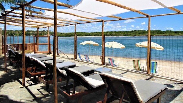 Un salon de plage doté de chaises longues et de parasols, offrant une vue sur une mer calme et une plage de sable.