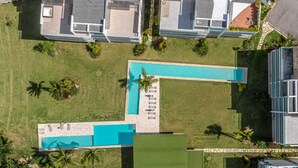 Luchtbeeld van een resort met een groot zwembad, meerdere gebouwen en palmbomen.
