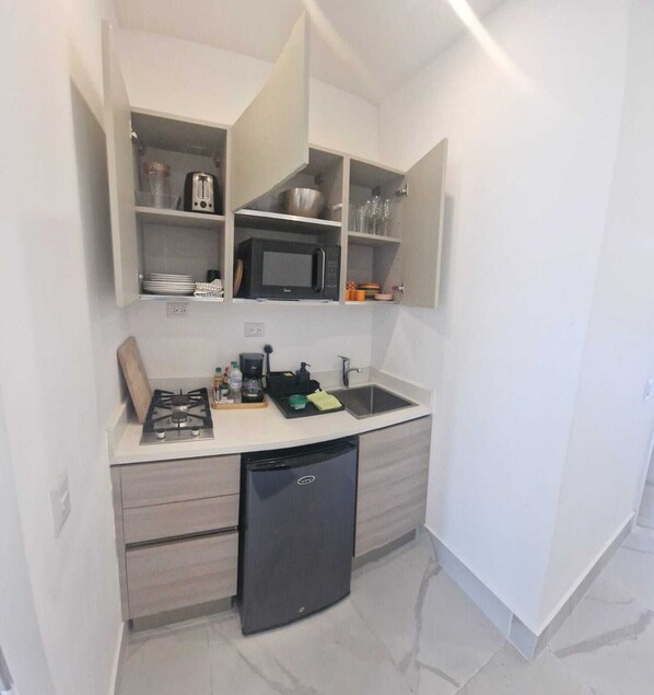 A compact kitchen with a built-in microwave, toaster, and shelves for dishes and glasses. - Studio, Residence Playa Bonita Front de mer (Las Terrenas)