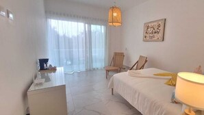 Een slaapkamer met een bed, een bureau, een stoel, een lamp en een raam met gordijnen.