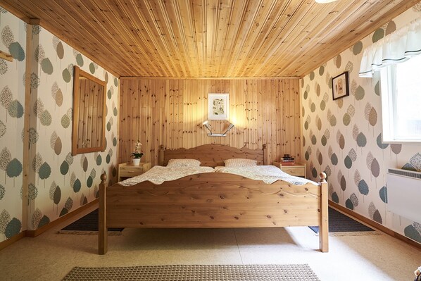 A wooden-paneled bedroom with a bed, nightstands, and a framed picture on the wall.
