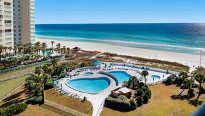 A hotel with a beachfront pool area, a beach, and a large building in the background. - 🚢Beachfront Complex-Private Beach-Incredible Gulf Views-Edgewater #1007🚢 (Miramar Beach)