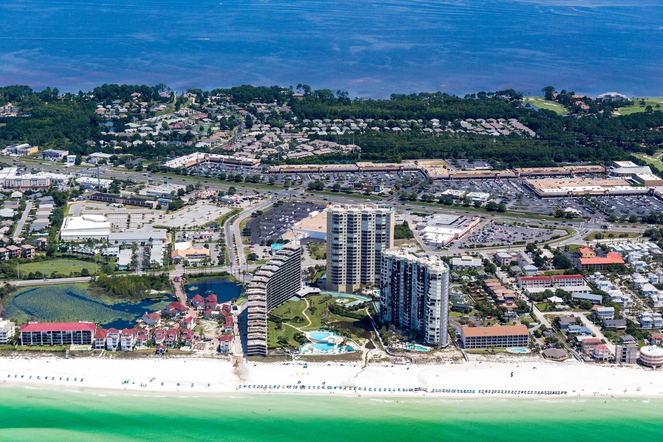 An aerial view of a coastal city with high-rise buildings, a marina, and a beach.