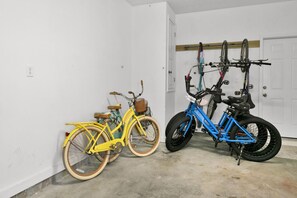 A garage with two bicycles, one yellow and one blue, and a door in the background. - 🐟Steps to Beach-30A-Legacy 502 Abalone (Santa Rosa Beach)