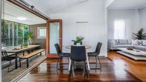A modern living room with a dining area, featuring a wooden bench, a round table, and a grey sofa. - Central Haven Milton 4BR Sleeps 10 (Milton)