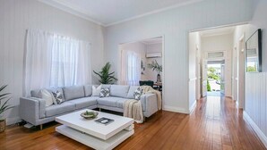 A spacious living room with a grey sectional sofa, a white coffee table, and wooden flooring. - Central Haven Milton 4BR Sleeps 10 (Milton)