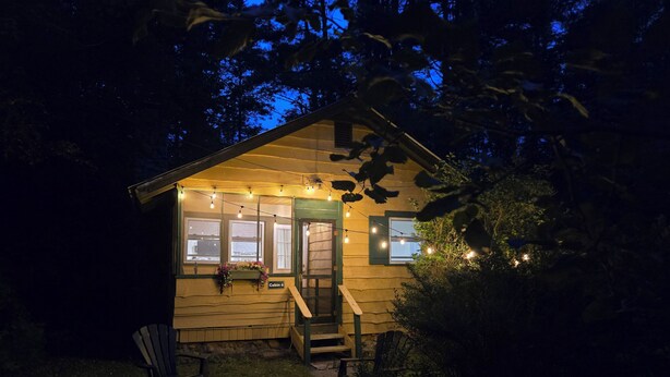A cabin with a porch, a bench, and a small garden area. - Butternut Adirondack Cabin. (Johnsburg)