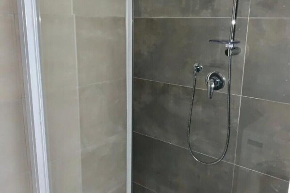 A shower area with a glass door and a showerhead.