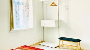 Habitació moderna amb un disseny minimalista, que destaca un gran mirall, una banca i un armari amb penjador.