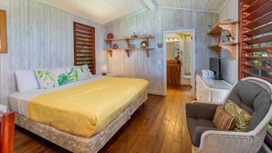 Een slaapkamer met een bed, een stoel, houten planken en een spiegel.