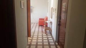 A hallway with a checkered floor, a red sofa, and a wooden door. - Bilocale Ariosto Vista Mare Laterale (Gallipoli)