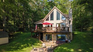 A two-story house with a deck, outdoor seating, and a hot tub.