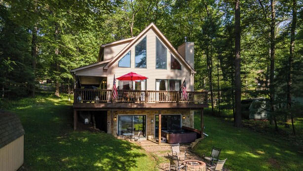 A two-story house with a deck, a hot tub, and a fire pit.