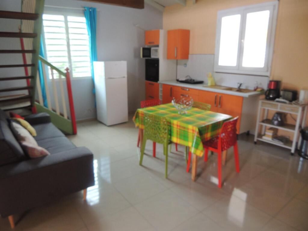 A compact living space with a dining area, kitchenette, and a staircase.