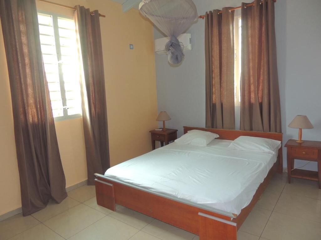 Un dormitorio con una cama de madera, dos mesitas de noche y cortinas en las ventanas.