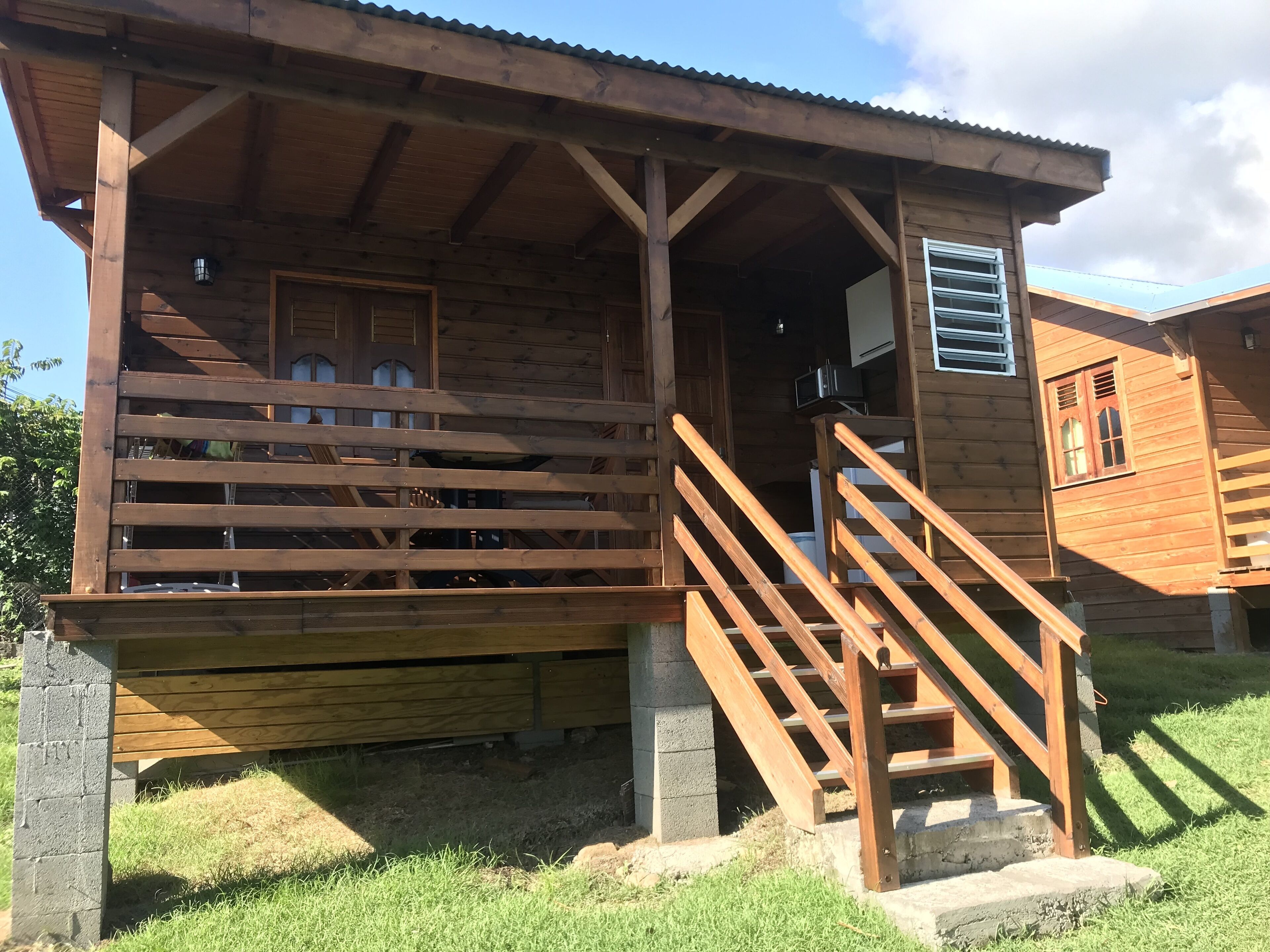 A wooden cabin with a porch, a staircase, and a window with shutters.