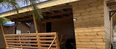A wooden cabin with a porch, a bench, and a small table.