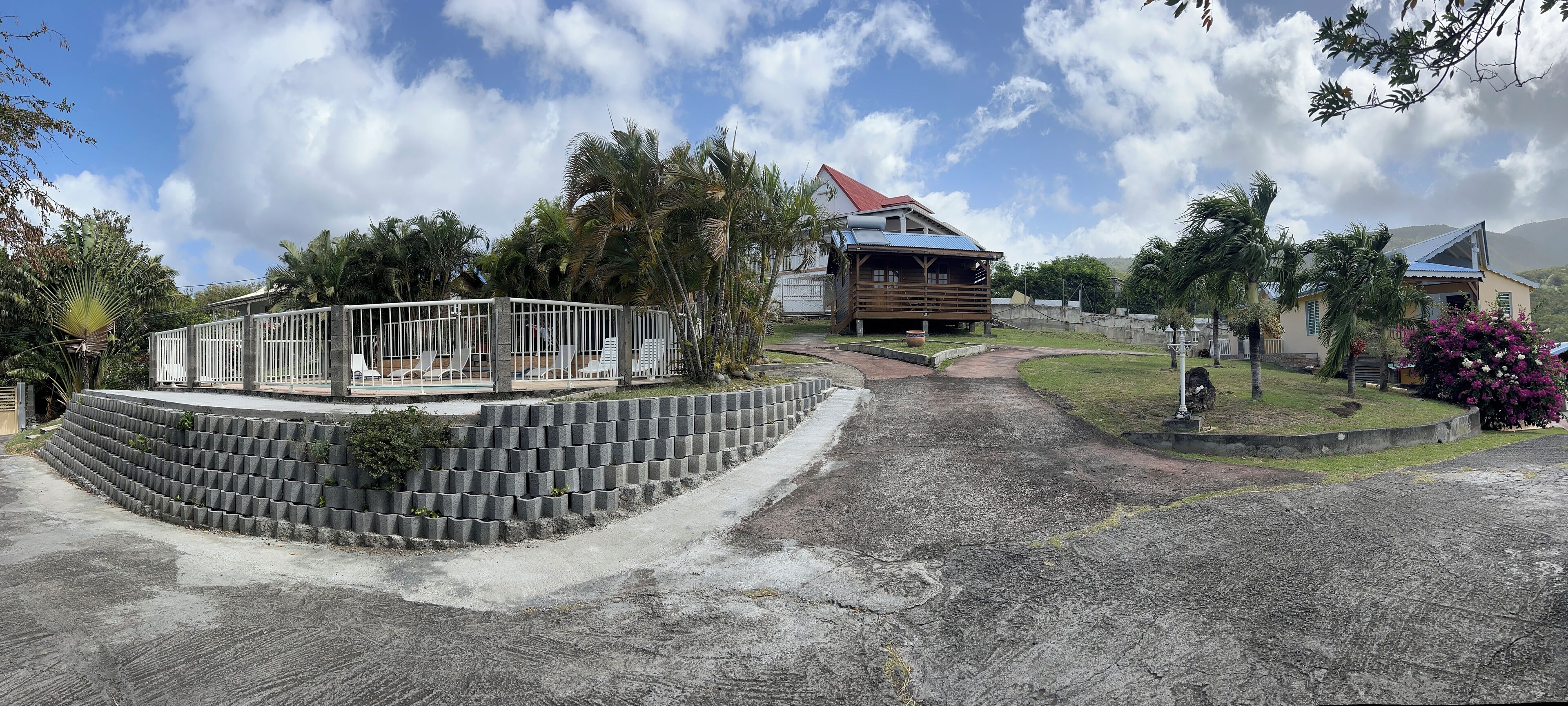 A resort with a pool area, palm trees, and a building with a red roof.