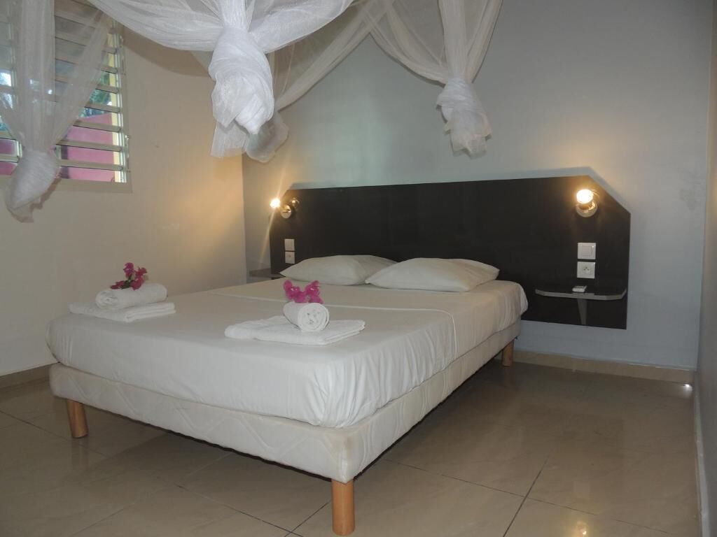 Una cama bien hecha con ropa blanca y un cabecero con luces empotradas.