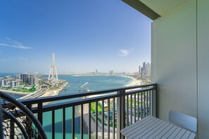 A balcony with a view of a coastal cityscape, including a tall tower and modern buildings. - Luxury StayCation - Spacious Modern Apt Overlooking The Arabian Sea (Dubai)