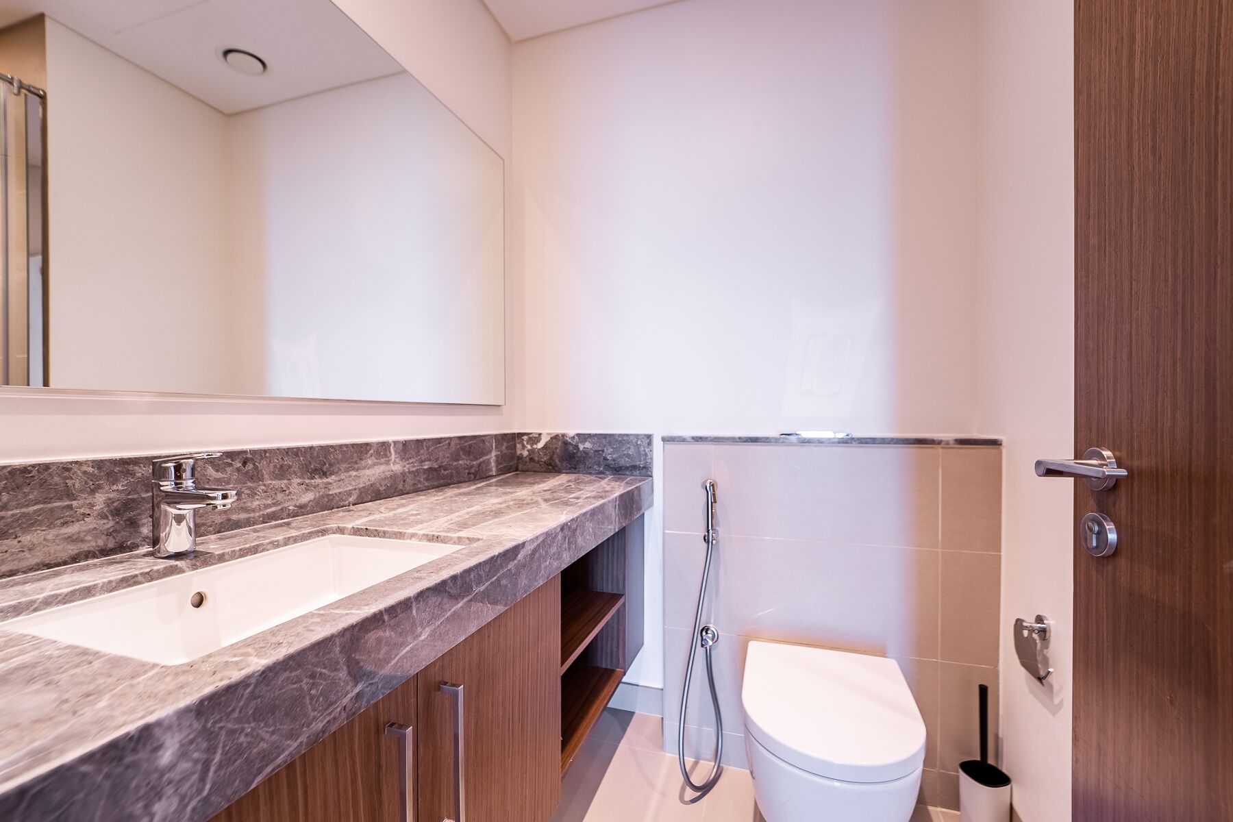 A modern bathroom with a marble countertop, a toilet, and a shower.