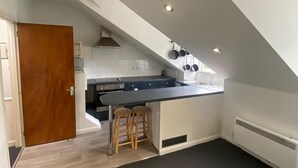 A modern kitchen with a dark countertop, wooden stools, and a built-in oven. - Apartment - Sleeps 4 & Excellent Transport Links (London)