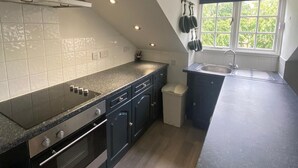 A modern kitchen with a large island, built-in oven, and a window with a view of greenery. - Apartment - Sleeps 4 & Excellent Transport Links (London)