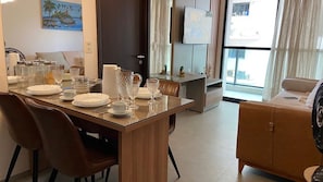 Ett modernt matområde med ett träbord för fyra personer, en soffa och en tv i bakgrunden.
