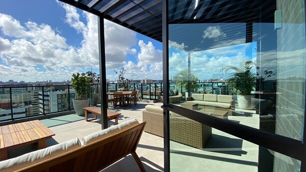A rooftop terrace with outdoor furniture, a dining area, and a view of the cityscape. - Apartamento na Ponta Verde - Maceio Alto Padrao Super Aconchegante (Ponta Verde Maceió)
