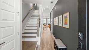 Un pasillo con una escalera, un comedor y obras de arte enmarcadas en la pared.