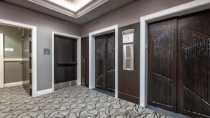 A hallway with three doors, each with a different design, leading to rooms. There is a carpet with a wavy pattern on the floor. - Downtown Nashville located in Printer's Alley with King Bed! (Nashville)