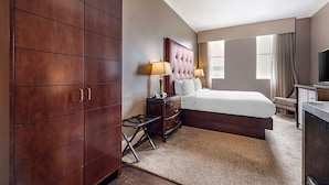 A hotel room with a large bed, a wooden wardrobe, a nightstand with lamps, and a television. - Downtown Nashville located in Printer's Alley with King Bed! (Nashville)