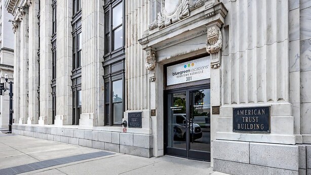 Exterior del American Trust Building, con un estilo arquitectónico clásico que destaca por sus grandes columnas y una entrada imponente.