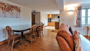 Una sala moderna con comedor, muebles de madera y una cocina al fondo.