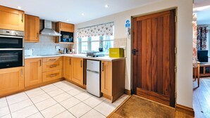 Una cocina moderna con armarios de madera, horno de acero inoxidable, microondas integrado y refrigerador.