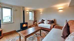 Una sala de estar acogedora con chimenea, un sofá, una mesa de centro y una alfombra estampada.
