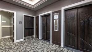 A hallway with three doors, each with a different design, leading to rooms. There is a carpet with a wavy pattern on the floor. - Downtown Nashville located in Printer's Alley with King Bed! (Nashville)