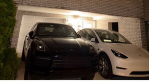 Un immeuble à plusieurs étages avec un garage, deux voitures garées devant et une entrée bien éclairée.