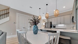 A modern kitchen with white cabinetry, a central island, and pendant lighting.